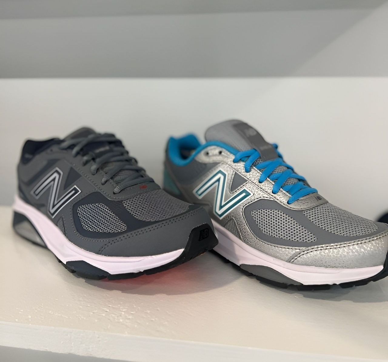 A pair of new balance shoes sitting on a shelf