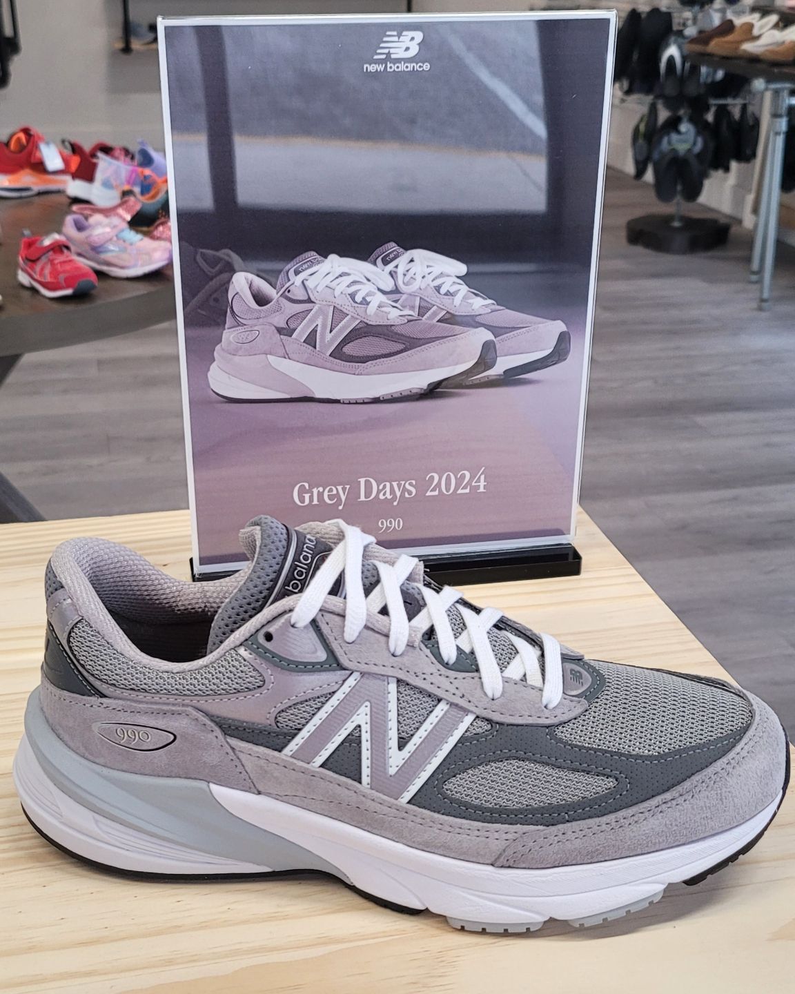 A pair of new balance shoes are sitting on a wooden table.