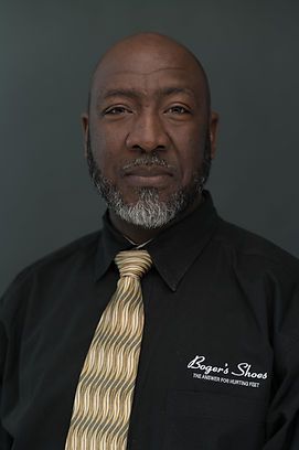 A man with a beard and mustache is wearing a black shirt and tie.