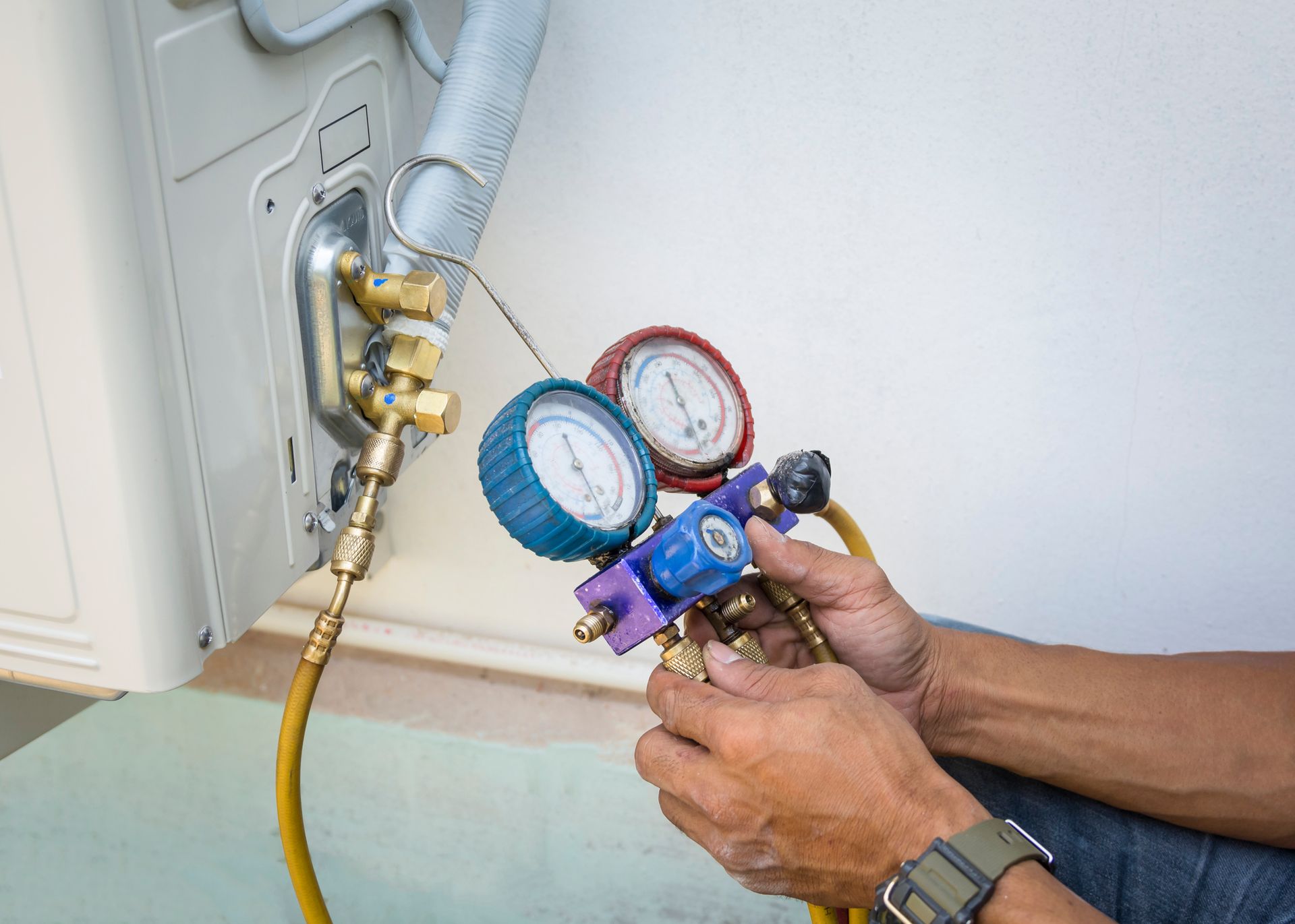 Technician using manometers for business refrigeration repair on air conditioning system.