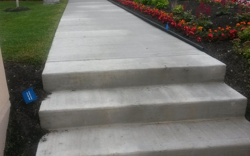 A concrete walkway with steps leading up to a garden.