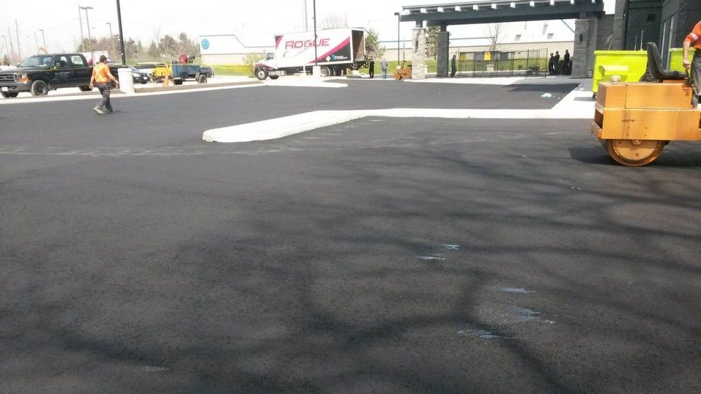 A man walking on a road with a yellow roller in the foreground