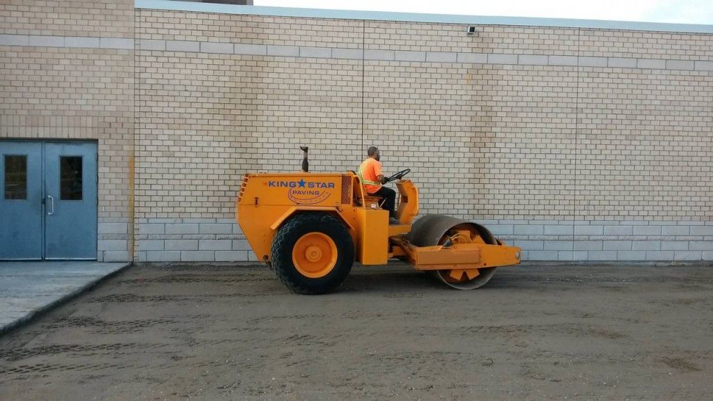 A yellow tractor is parked in front of a brick building