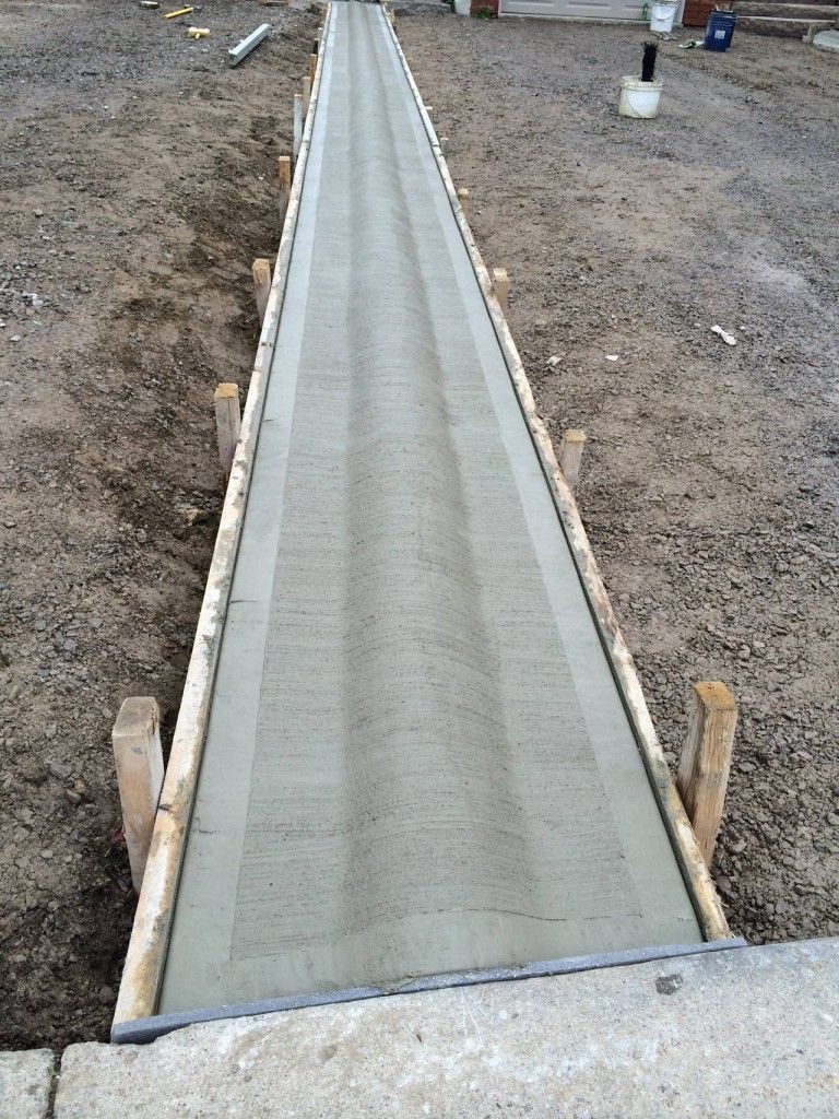A concrete walkway is being built in a dirt field.