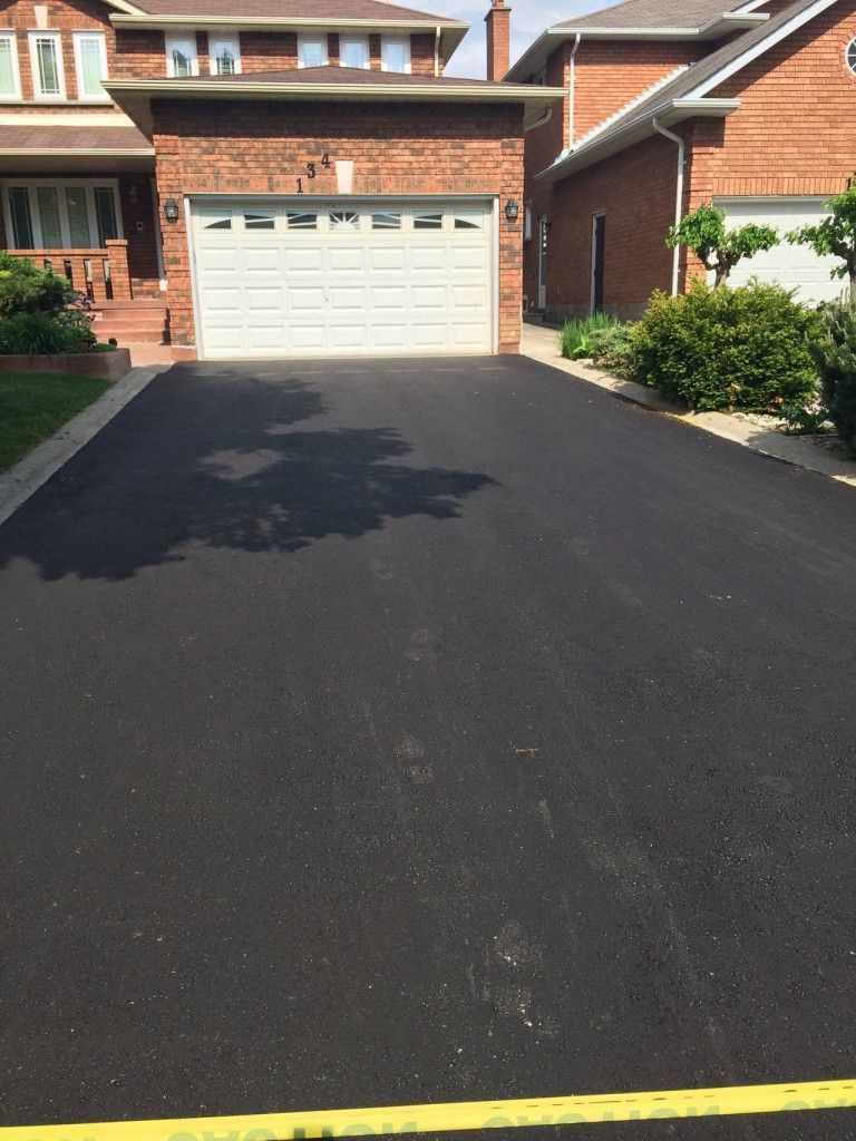 A driveway leading to a brick house with a white garage door