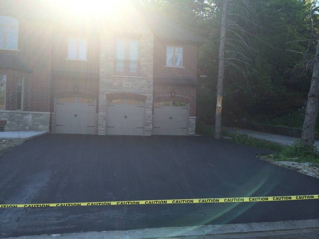 A brick house with two garage doors is surrounded by yellow tape.