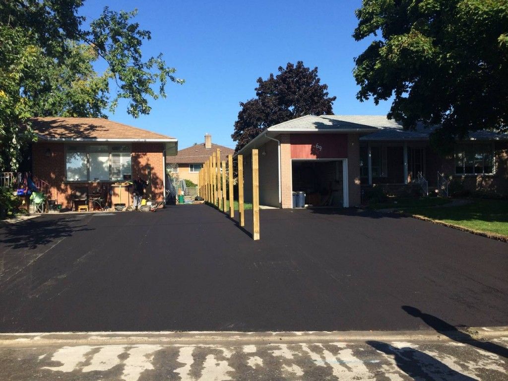 A house with a black driveway and a wooden fence