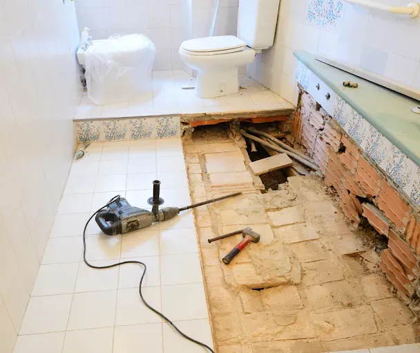 A bathroom under construction with a toilet and a hammer on the floor.