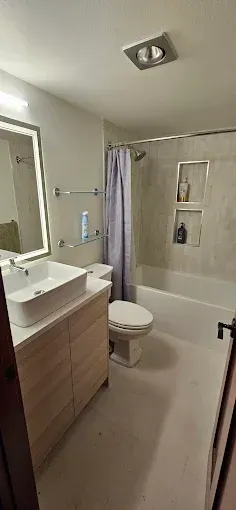 A bathroom with a sink , toilet , tub and mirror.