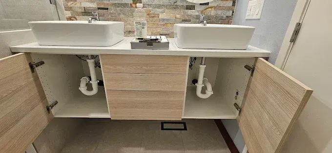A bathroom with two sinks and a vanity with the doors open.