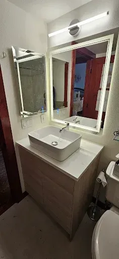 A bathroom with a sink , mirror and toilet.