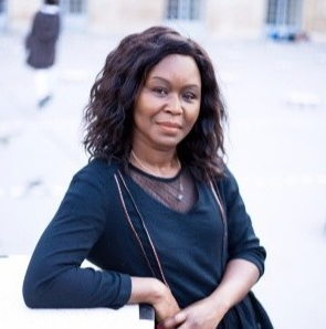 Une femme en robe noire sourit à la caméra