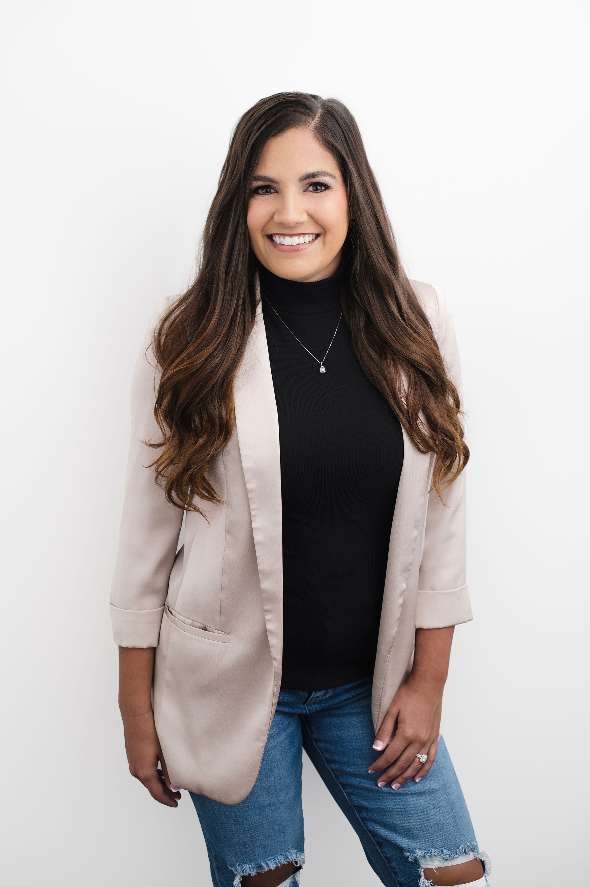 A woman is sitting at a desk with a laptop and a vase of flowers.