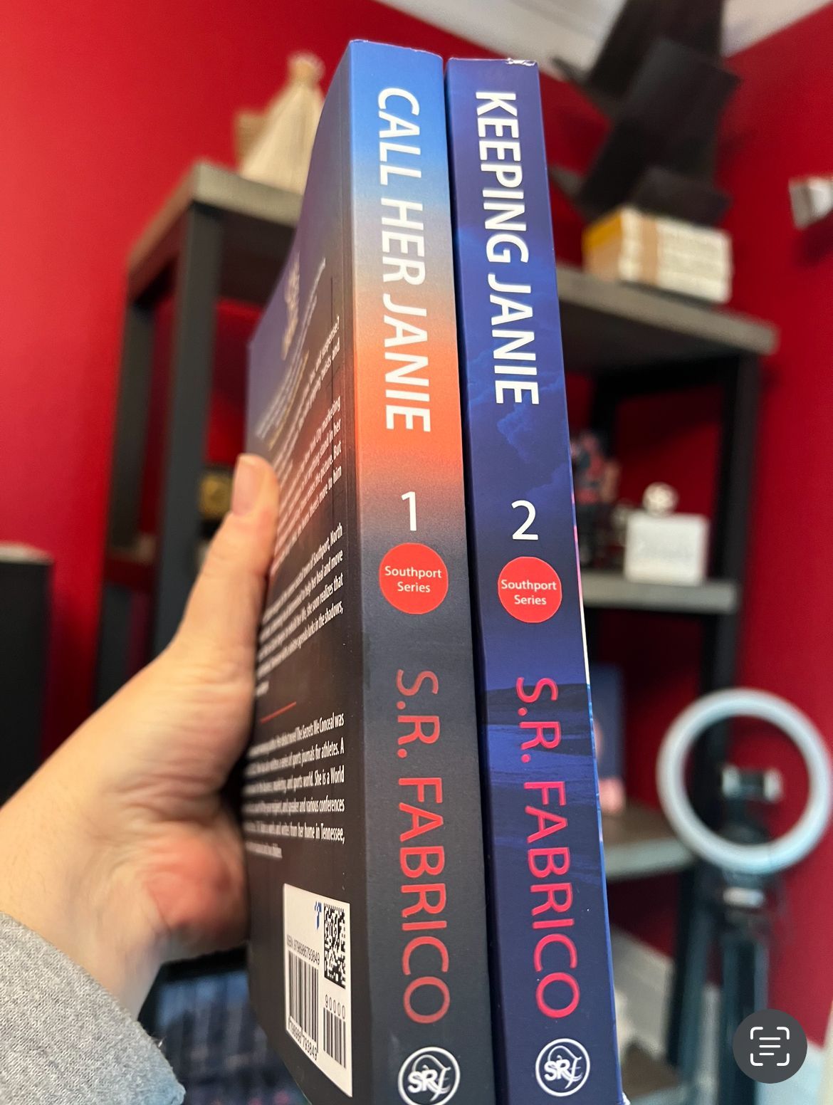 A person is holding two books titled call her janie and keeping janie