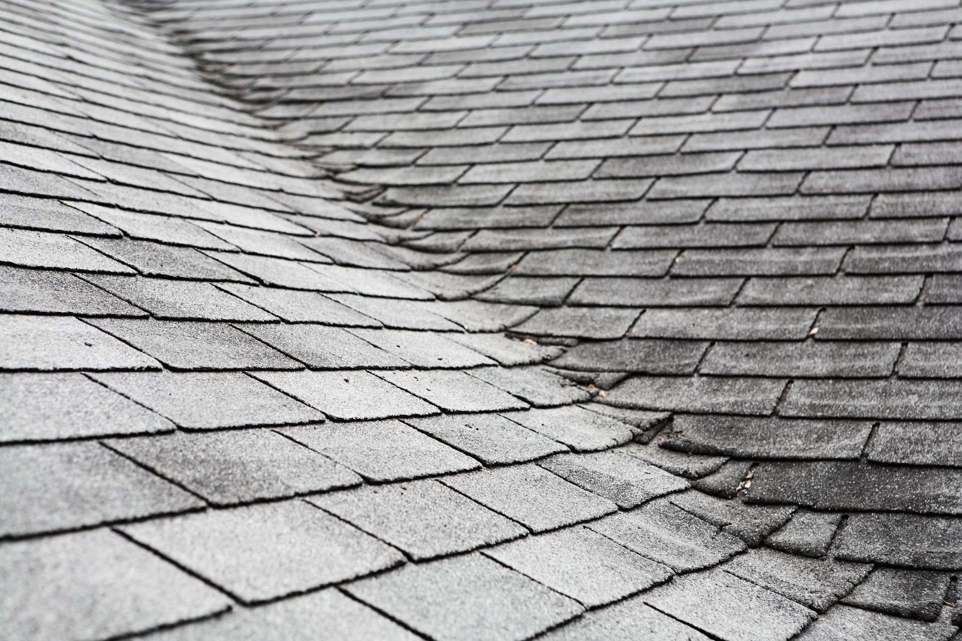 Red clay roof tiles being installed on a roof with visible wooden beams and black underlayment.