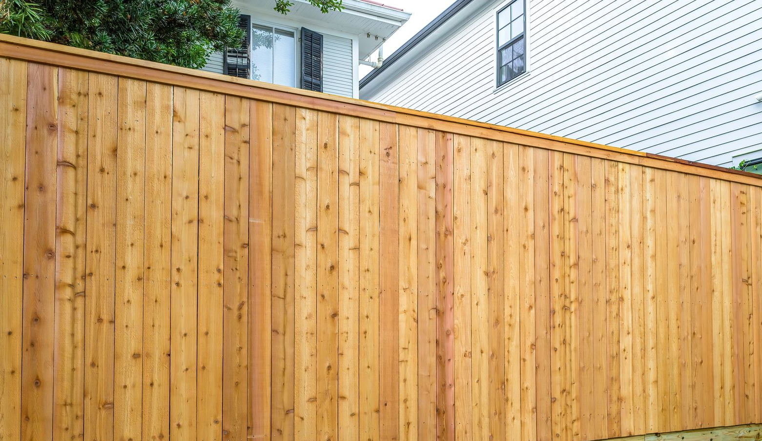 Hand painting a black metal fence with a yellow handled brush.