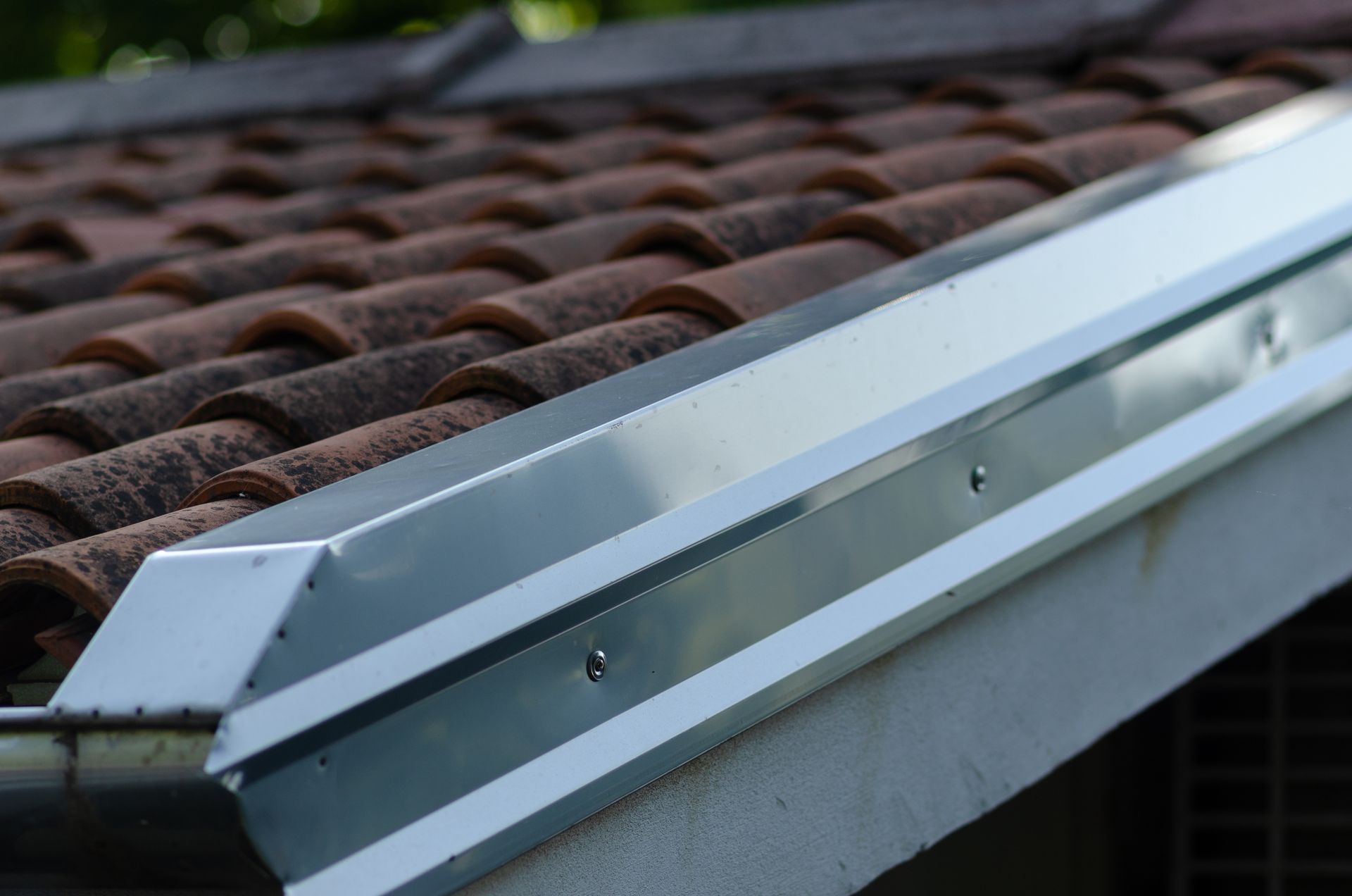 Close-up of a house roof with red tiles and a metallic gutter, capturing a building's architectural detail.
