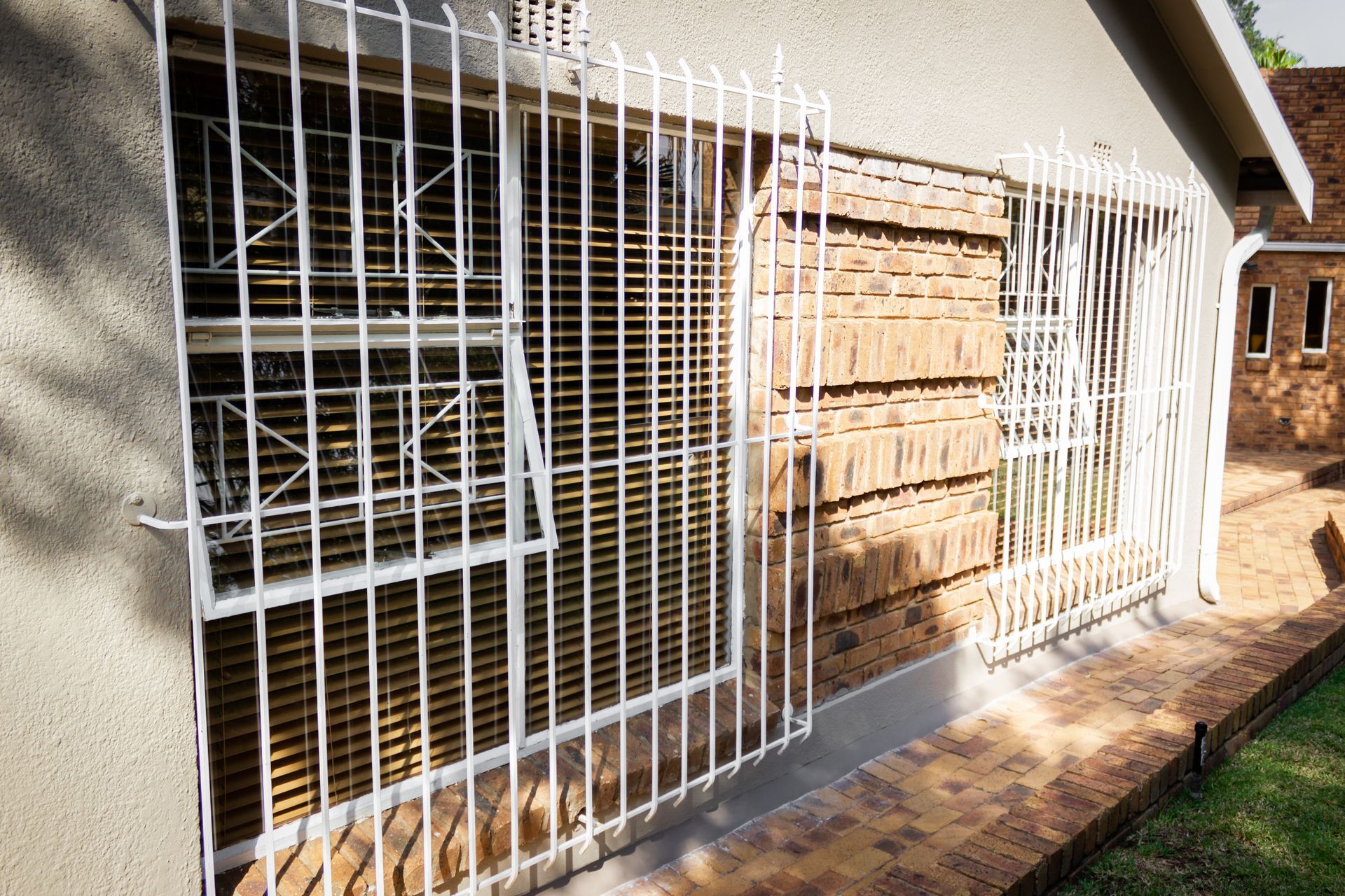 White barred windows on a brick and stucco building, offering security.