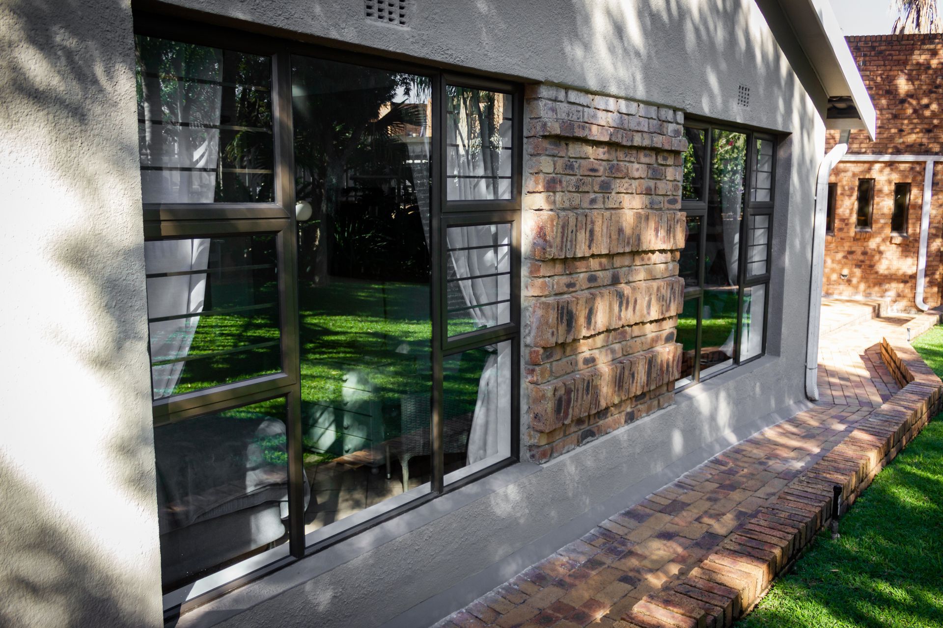 Building exterior with windows, brick accents, and a brick walkway.