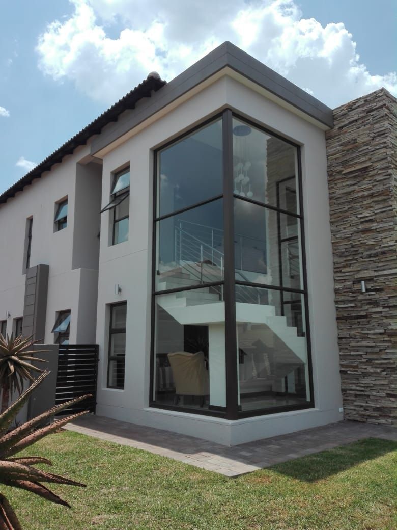 Modern two-story house with large glass windows showcasing interior staircase.