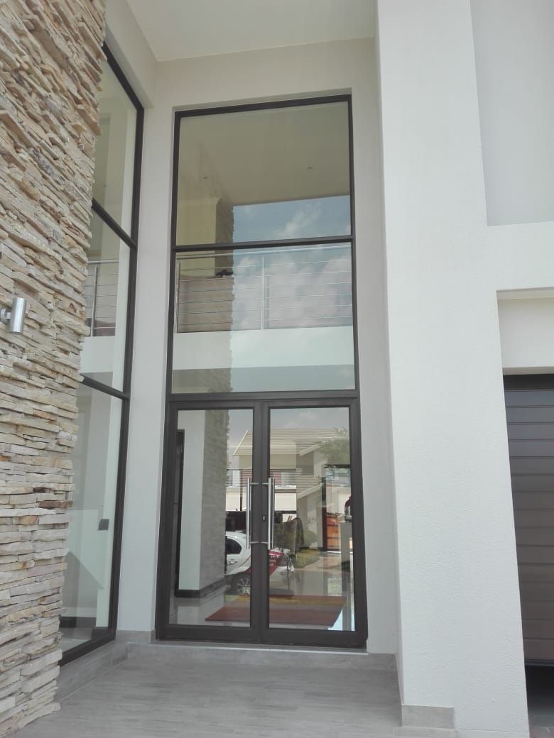 Glass front entrance with double doors, sidelights, and upper transom window in a modern home.