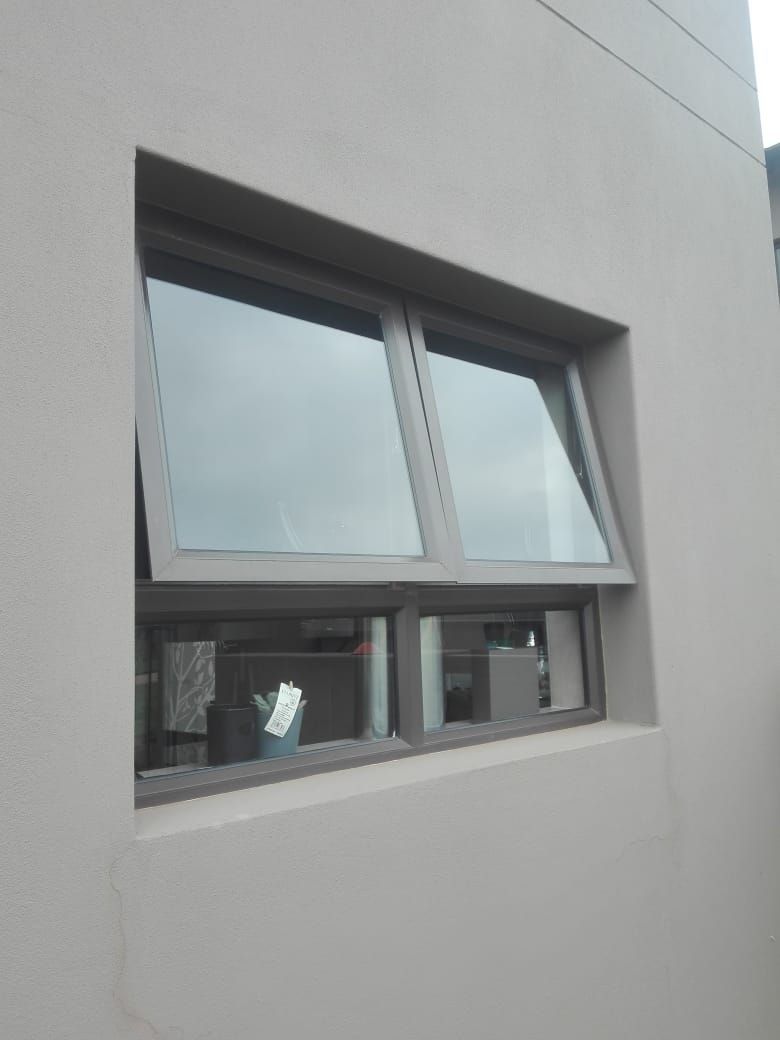 Gray awning window partially open on a light beige exterior wall.
