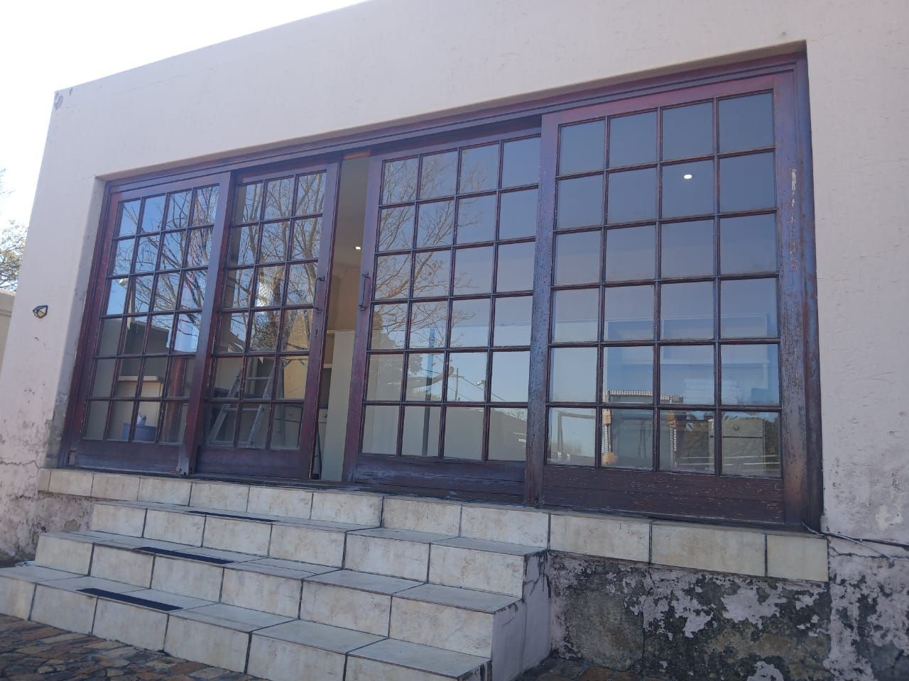 Three wooden-framed glass doors on a building, with steps in front.