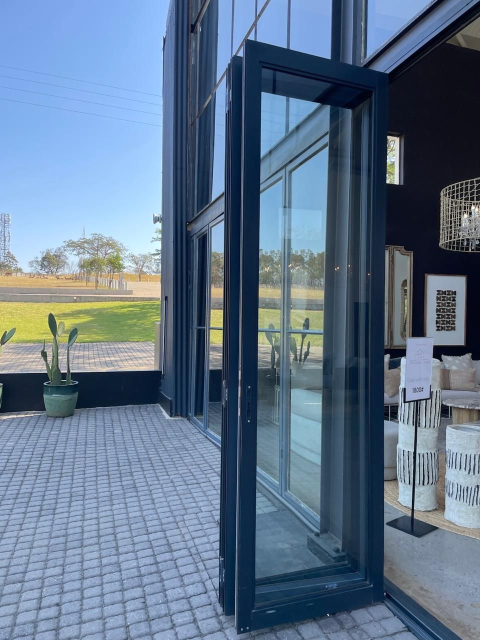 Glass doors open onto a patio, revealing an outdoor field and inside furniture.