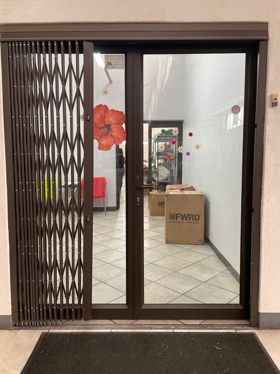 Brown sliding door with security gate, leading into a room with boxes and floral decorations.