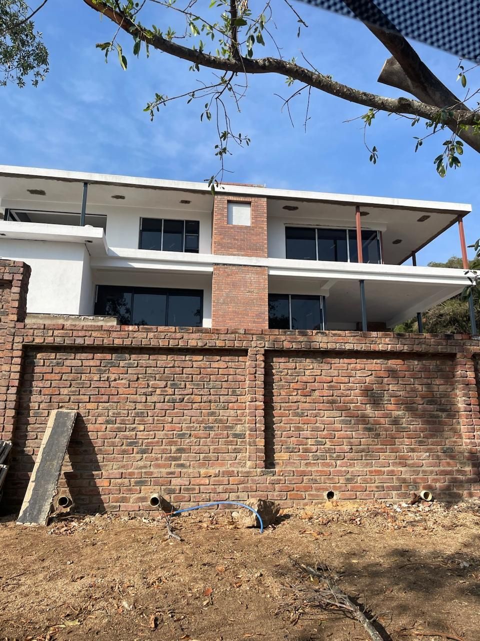 Two-story modern home with brick fence and exterior, clear blue sky.