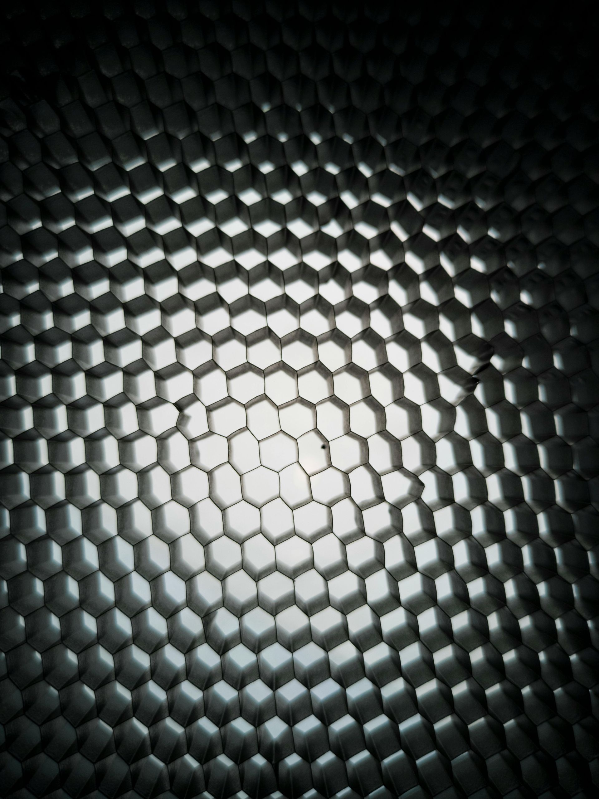 Honeycomb grid pattern, centrally illuminated, appearing metallic.