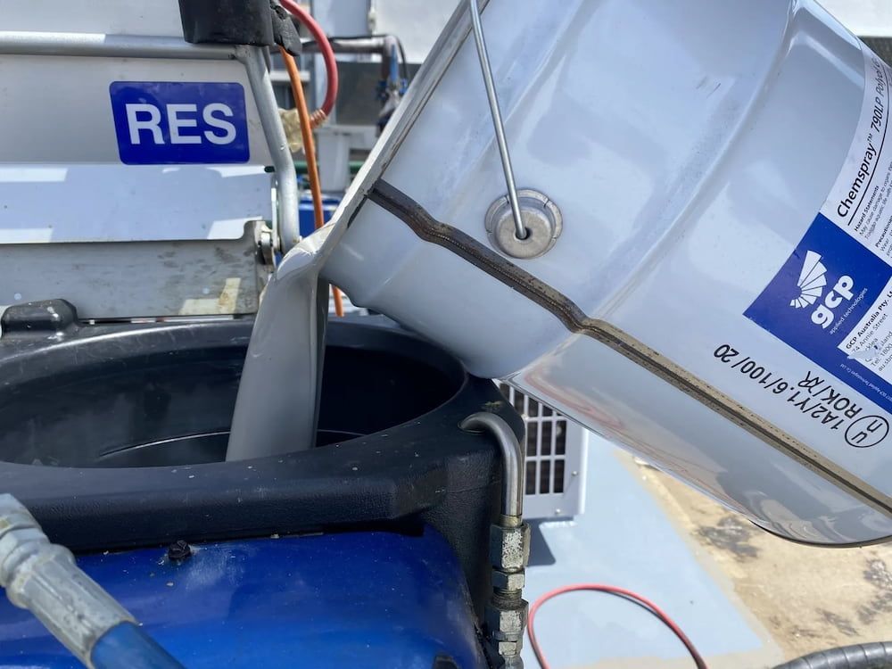 A Bucket of Gray Liquid Being Poured Into a Dark Blue Container — Unique Waterproofing Solutions in North Rocks, NSW