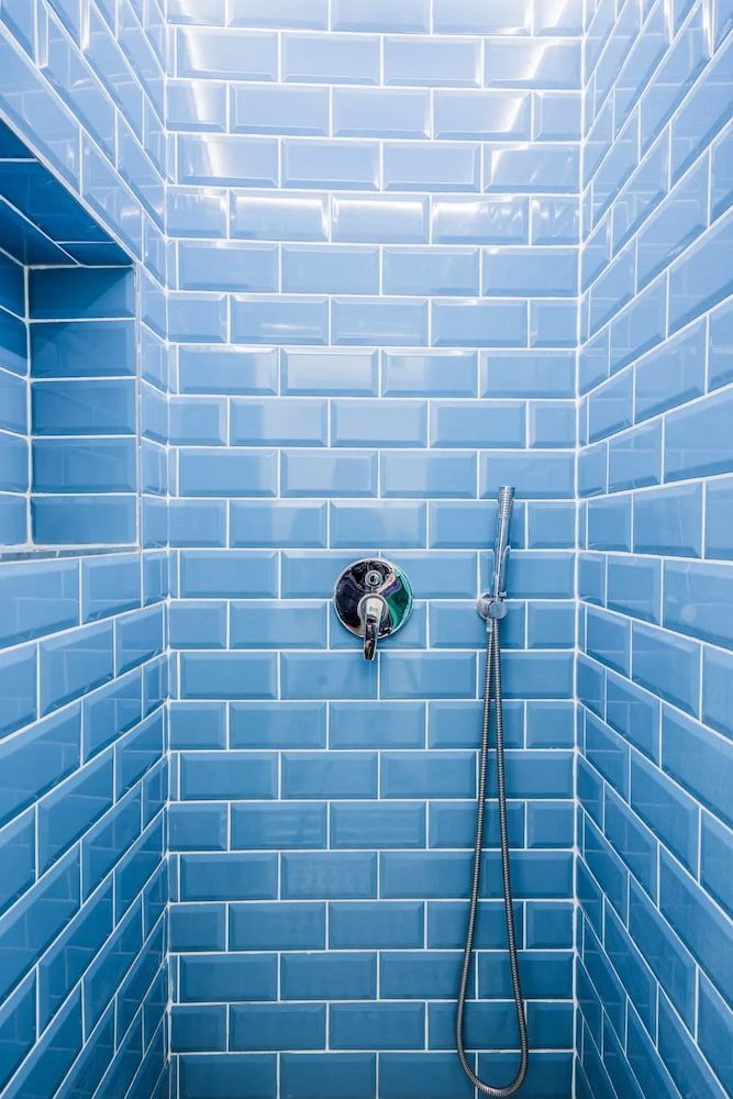 Blue Tiled Shower Stall With a Built-in Shelf and Chrome Shower Fixture — Unique Waterproofing Solutions in North Rocks, NSW
