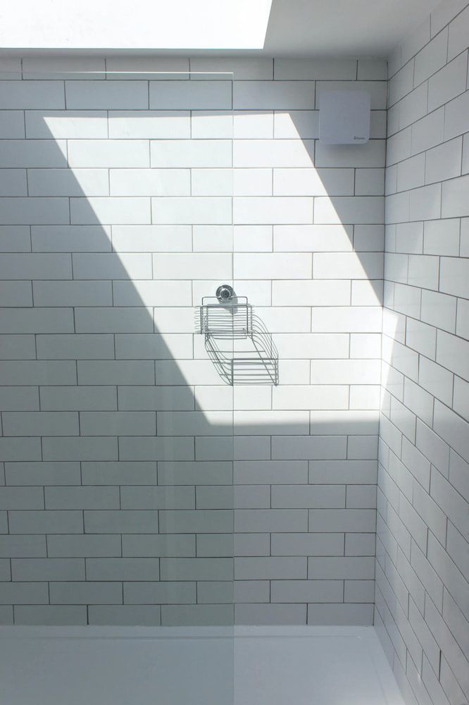White Tiled Shower With Glass Door, Skylight Casting Strong Light — Unique Waterproofing Solutions in North Rocks, NSW