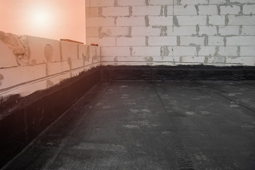 Black roofing material installed on a flat surface, with concrete block walls. — Unique Waterproofing Solutions in North Rocks, NSW