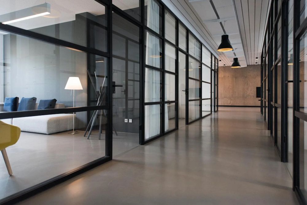 Modern Office Hallway With Glass-walled Rooms and Gray Flooring — Unique Waterproofing Solutions in North Rocks, NSW