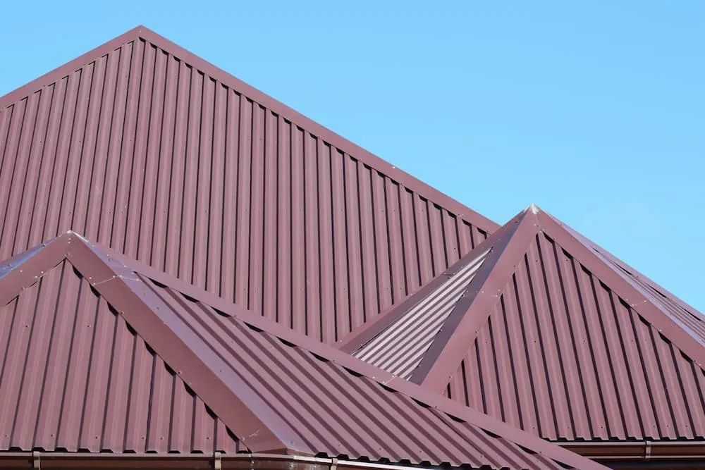 Brown Metal Roof With Vertical Ridges Against a Bright Blue Sky — Unique Waterproofing Solutions in North Rocks, NSW