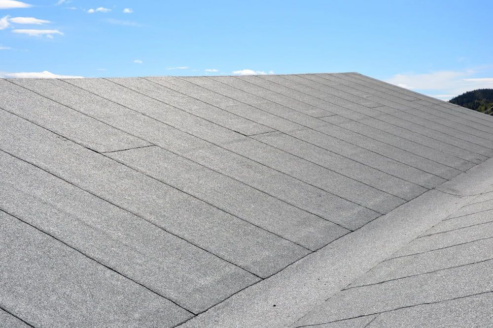 Gray asphalt shingle roof on a house, angled upward with a blue sky in the background. — Unique Waterproofing Solutions in North Rocks, NSW