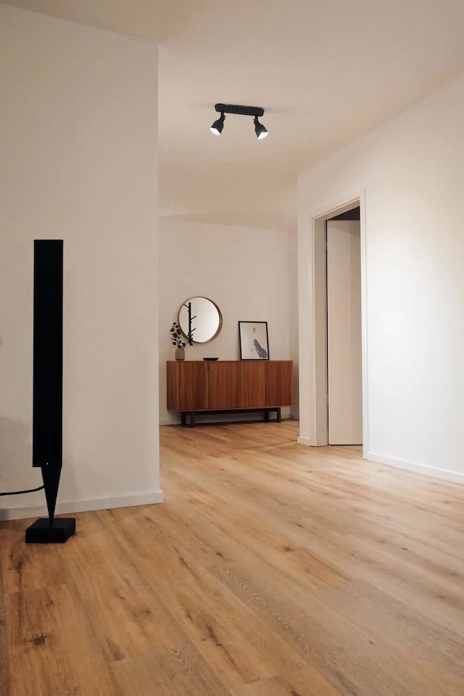 Wooden-floored interior with white walls. A black speaker stands near the entrance. A wooden cabinet and mirror are visible. — Unique Waterproofing Solutions in North Rocks, NSW