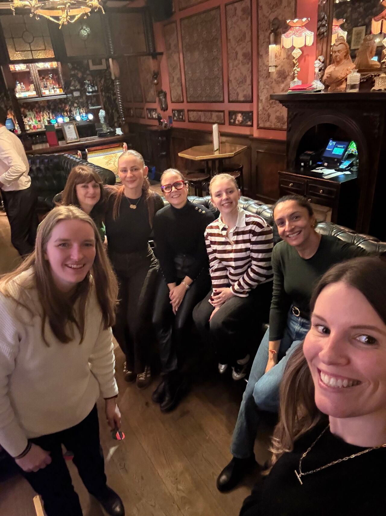 A group sits at a conference table during a meeting with an agenda projected on a screen in a modern office space.