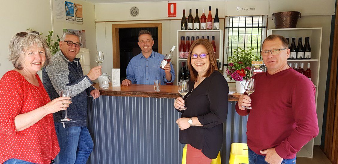3 guys and 2 woman infront of the wine rack