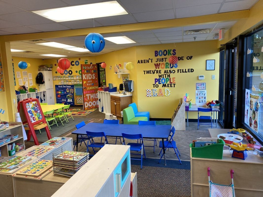 A brightly-colored preschool classroom with books, tables, and decorations.