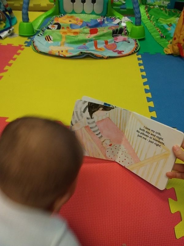 Baby looking at a book on a colorful play mat.