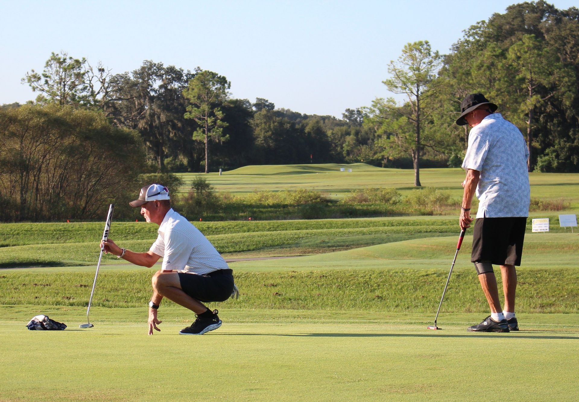 Two men are playing golf on a lush green field