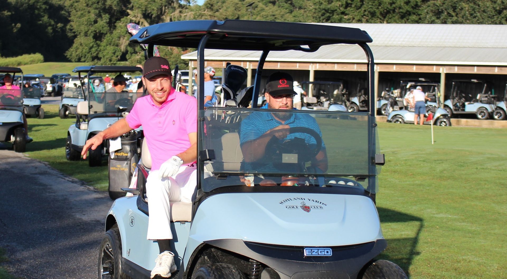 Two men are sitting in a golf cart on a golf course.