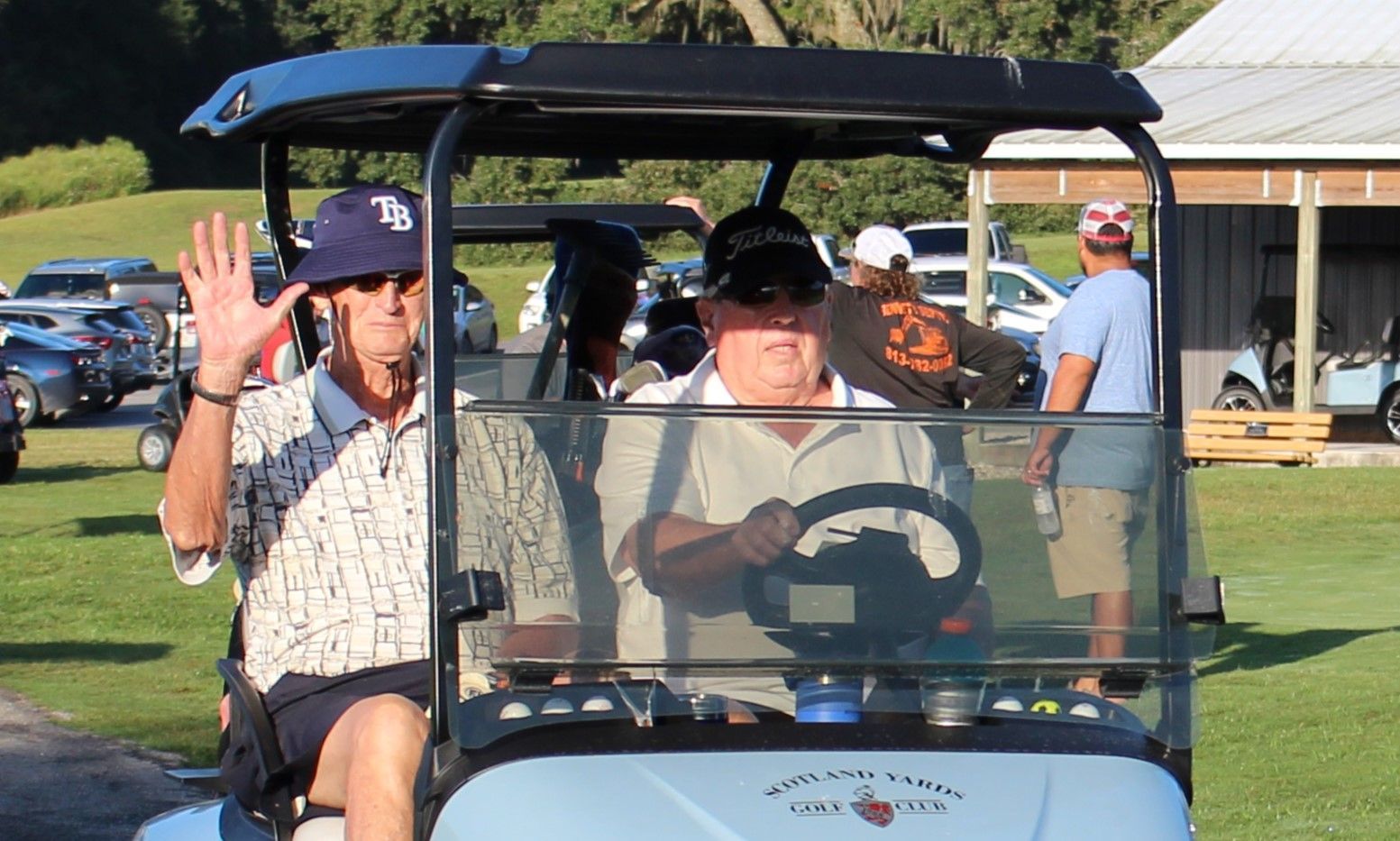 Two men are sitting in a golf cart on a golf course.