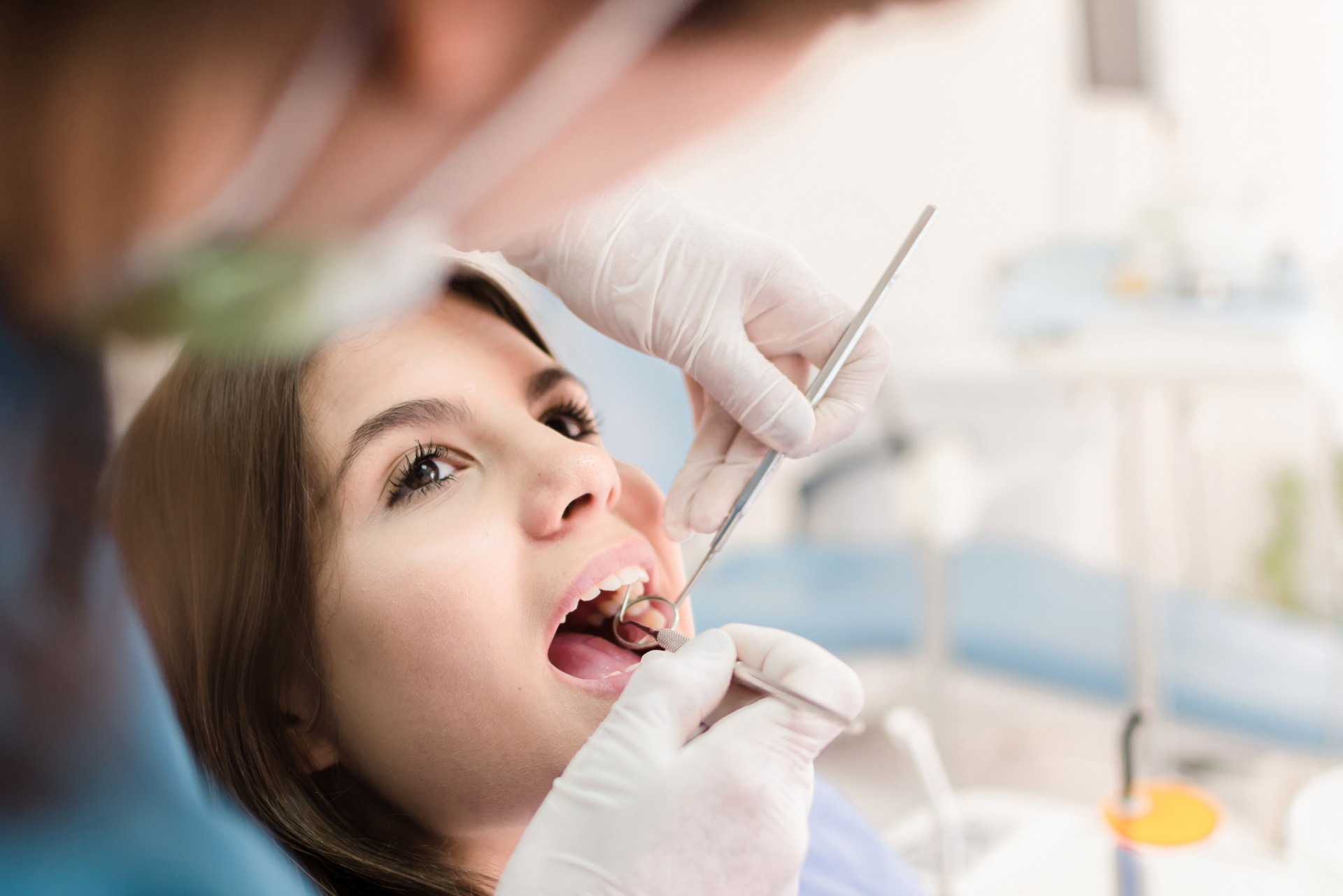 A woman is getting her teeth examined by a dentist in a dental chair.