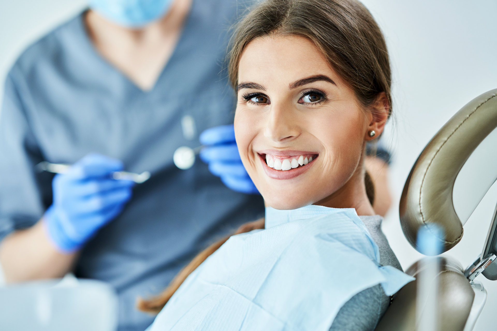 A woman is smiling while sitting in a dental chair.