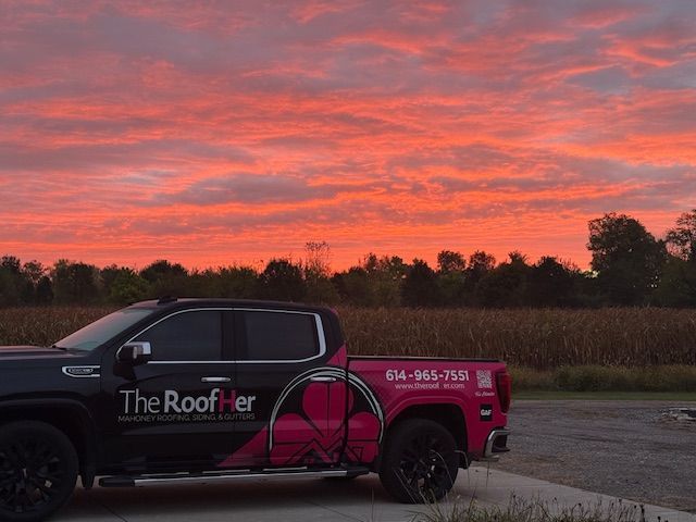 Pickup truck with “The Roofer” branding parked at sunset under a pink sky