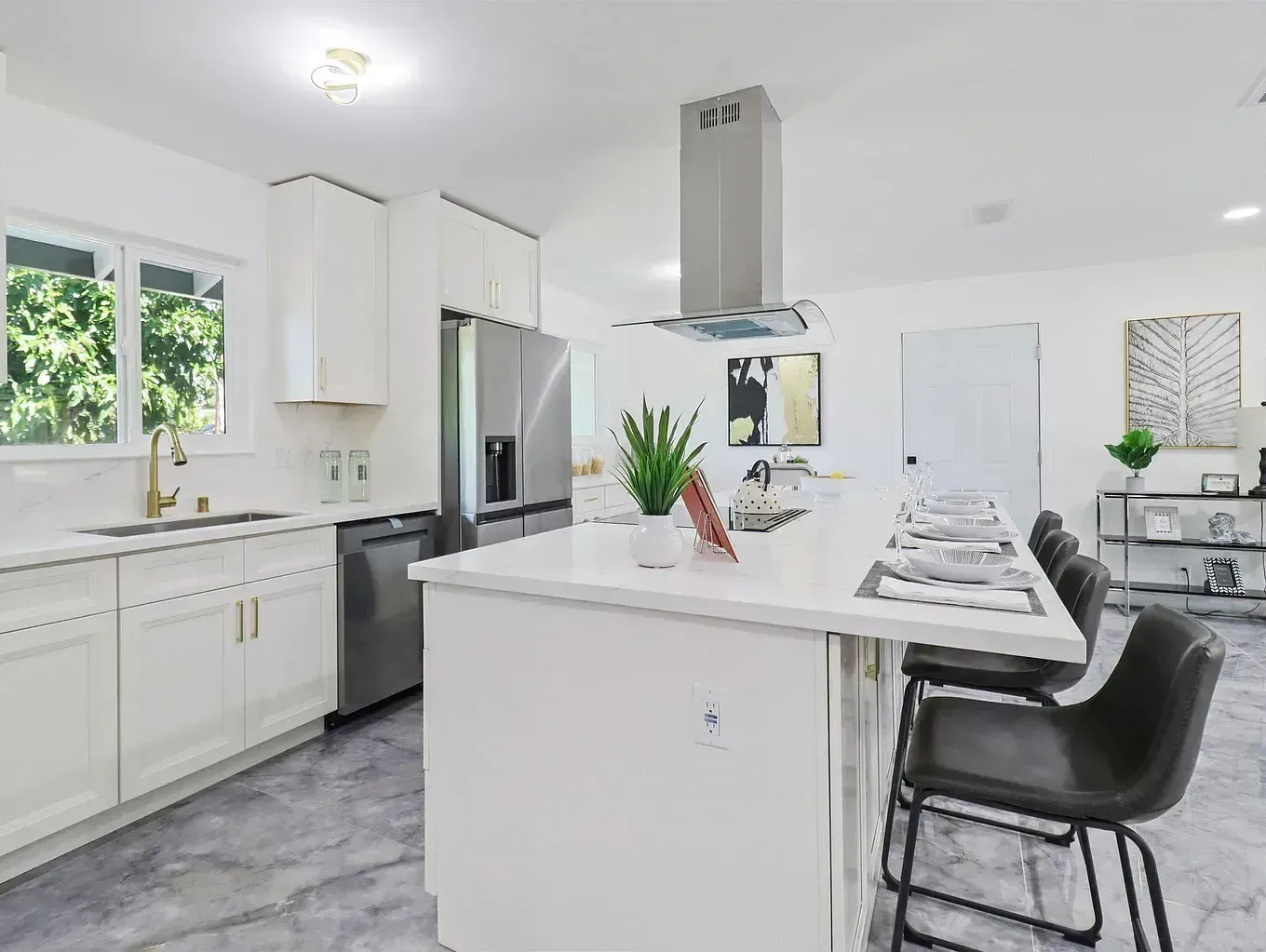 A kitchen with white cabinets , stainless steel appliances and a large island.